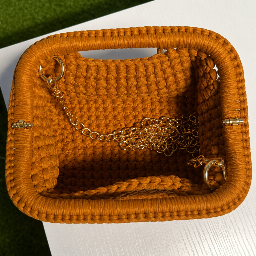Interno clutch intrecciata caramello con catena dorata stile fucsia